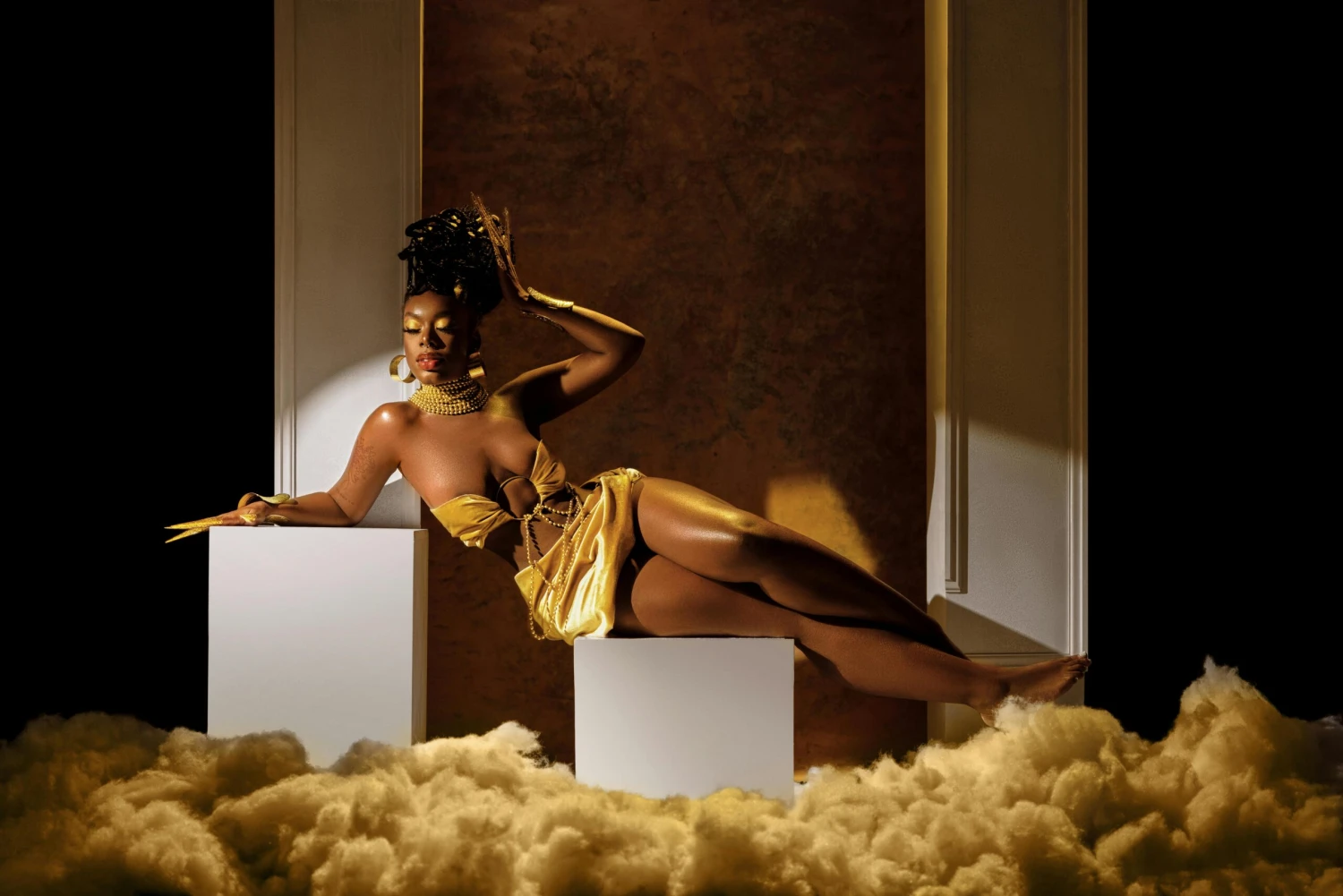 Stylish portrait of a woman in a golden dress posing elegantly in a studio environment.